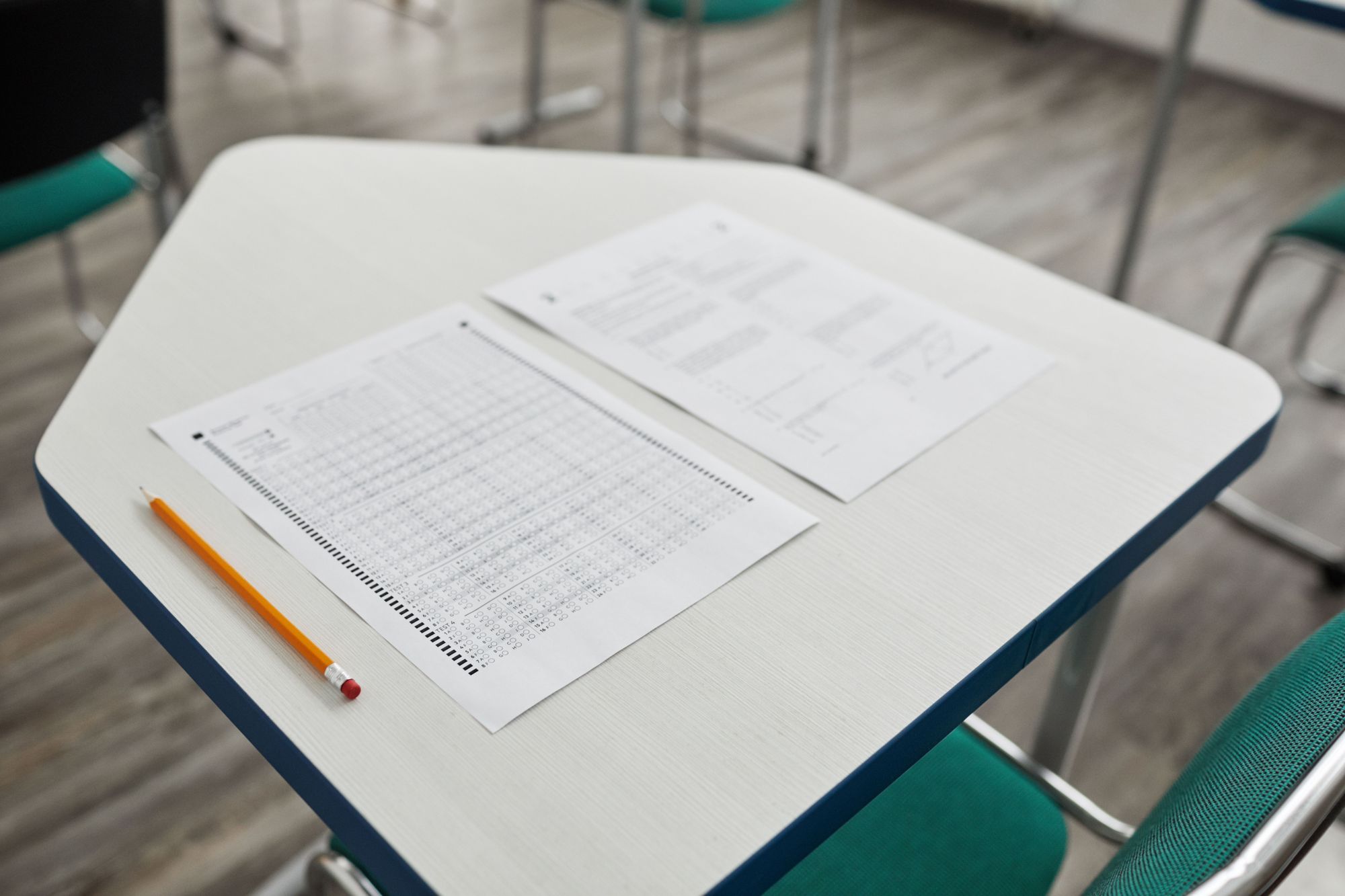 A bubble answer sheet, a question paper and a pencil laid out on an exam-hall desk