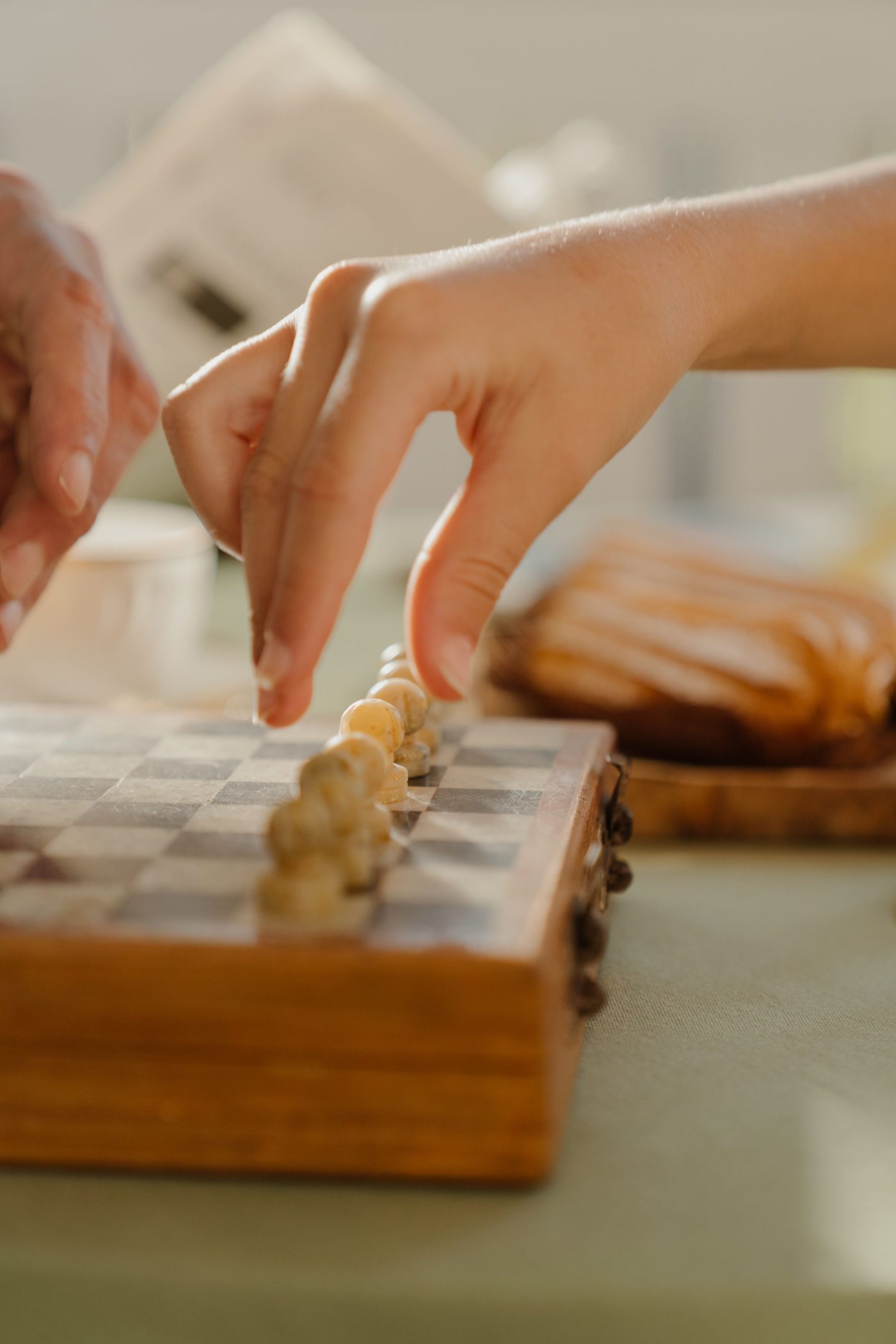 A hand lining up wooden pawns on a small folding chessboard