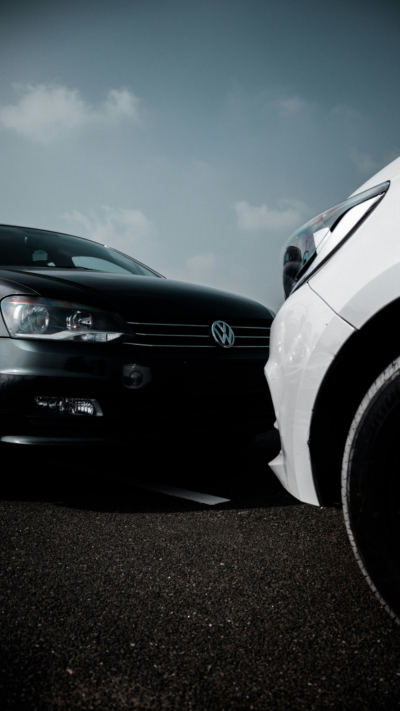 A black car and a white car parked nose to nose, almost touching