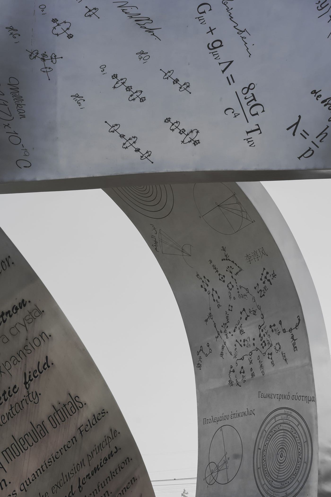 A curved steel sculpture engraved with physics equations, including Einstein's field equations